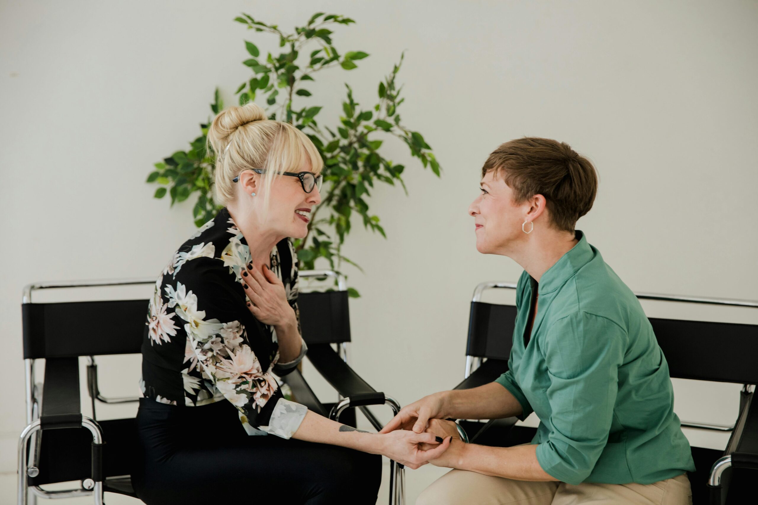 Two women sitting together, sharing a supportive and positive interaction indoors.